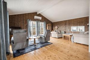 a living room with two chairs and a couch at Hytte med peis utsikt & lakseelv rett nedenfor! in Lødingen