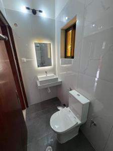 a white bathroom with a toilet and a sink at The 3 Little Pigs apartments in Sidari +20 photos