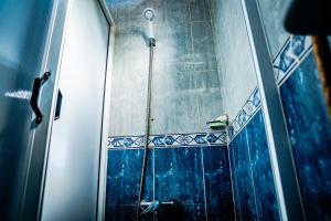 a shower in a bathroom with blue tiles at Dinosaur Anza Surf House in Agadir +64 photos