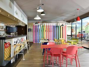 a restaurant with a red table and chairs at ibis Styles Angoulême Nord in Champniers