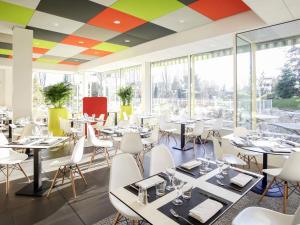 a dining room with tables and chairs and windows at ibis Styles Nancy Sud in Houdemont