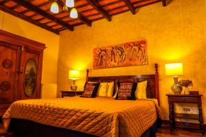 a bedroom with a bed with two lamps and a painting on the wall at Villa de Antaño in Antigua Guatemala
