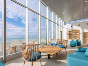 a room with a table and chairs and windows at Novotel Thalassa Le Touquet in Le Touquet-Paris-Plage