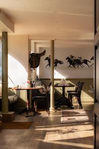 a dining room with two tables and a wall with horses on it at The Wensleydale Hotel in Middleham