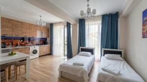 a bedroom with two beds and a table and a kitchen at Cozy Almaty Escape in Almaty