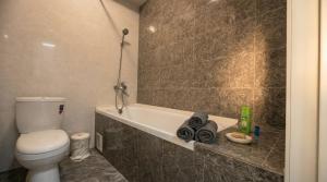 a bathroom with a toilet and a bath tub at Cozy Almaty Escape in Almaty +1 photo