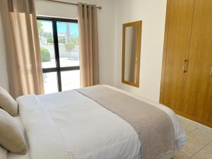 a bedroom with a white bed and a window at Villa Tara Christina in Carvoeiro