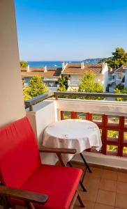 a red chair and a table on a balcony at Villa Estrella - Pool - Sunset Views - 200m Siviri Beach in Siviri