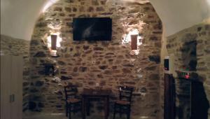 a room with a stone wall with a tv and chairs at Pyrgos Mitsakou in Vathia