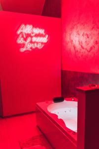a red bathroom with a tub and a neon sign at Afrodite suite room in Brindisi