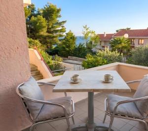 a table and chairs on a balcony with two cups at Villa Estrella - Pool - Sunset Views - 200m Siviri Beach in Siviri