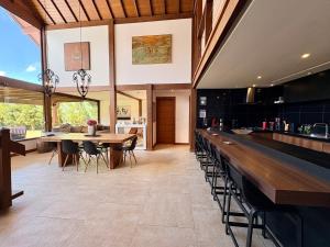 an open kitchen and dining room with a long bar at Casa 04 Monte Boa Vista - Conforto com Piscina Privativa, Sauna e Lareira in Teresópolis +44 photos