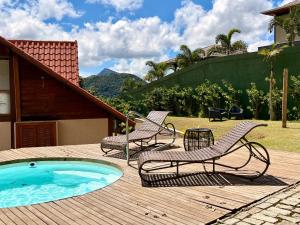two chairs and a swimming pool on a wooden deck at Casa 04 Monte Boa Vista - Conforto com Piscina Privativa, Sauna e Lareira in Teresópolis