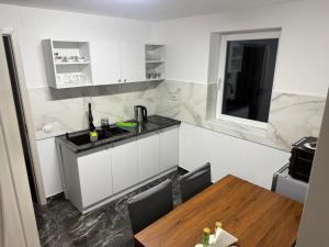 a kitchen with white cabinets and a wooden table at Alex88 in Buşteni