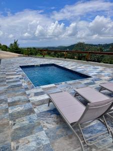 a swimming pool with two lounge chairs on a patio at Studio Splash 2 personnes piscine chauffée in Rivière-Salée