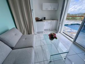 a living room with a couch and flowers on the floor at Studio Splash 2 personnes piscine chauffée in Rivière-Salée