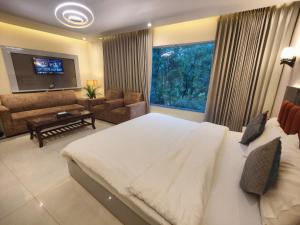 a bedroom with a large bed and a living room at Nirvana Bliss By Cosy Homes, Malsi in Dehradun