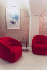 two red chairs and a table in a living room at Afrodite suite room in Brindisi