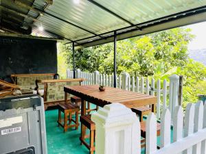 a wooden table on a patio with a white fence at Kandy Green HillTop Hotel in Kandy