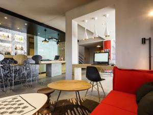 a living room with a red couch and a bar at ibis Lorient Centre Hôtelier in Caudan