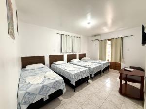 a bedroom with two beds and a table at Pousada Granville in Campina Grande