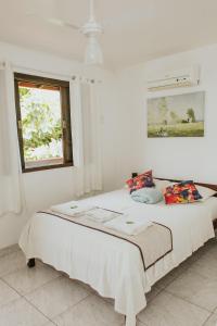 a white bedroom with a large bed with a window at Pousada Piratininga in Niterói +76 photos