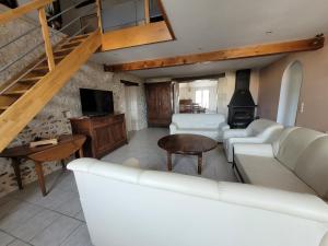 a living room with a white couch and a tv at Gîte de La Rev'rie in Montalembert
