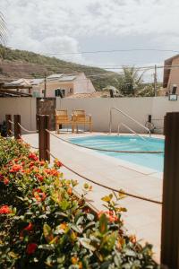 a swimming pool with two chairs and flowers at Pousada Piratininga in Niterói