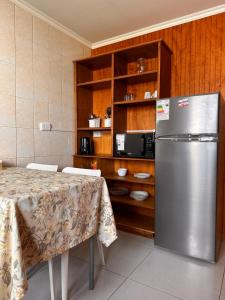 a kitchen with a table and a stainless steel refrigerator at Cabañas Bosque Sur in Puerto Varas