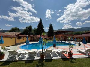 a swimming pool with lounge chairs and umbrellas at Hotel Paradise in Kyustendil