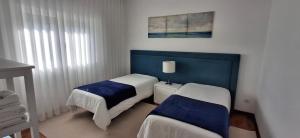 a bedroom with two beds and a blue headboard at Ribeiro´s House in Gafanha da Nazaré