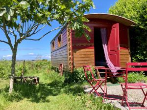an old caravan with two chairs and a table and a tree at Les Chambres du Mad in Henvic