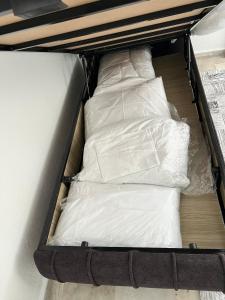 a bed with white sheets and pillows on it at BR Konaklama in Göztepe