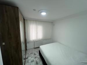 a white bedroom with a bed and a window at BR Konaklama in Göztepe