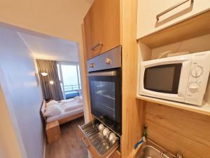 a small kitchen with a microwave and a living room at Appartement Serges mit Pool und Sauna in Freyung in Freyung