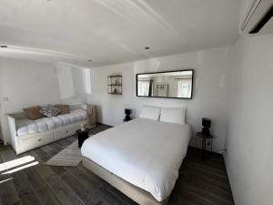 a bedroom with a white bed and a couch at Maison avec Jacuzzi Privatif Calme Soleil Cote d Azur in La Crau