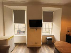 a living room with two windows and a flat screen tv at Edinburgh Town Apartment in Edinburgh