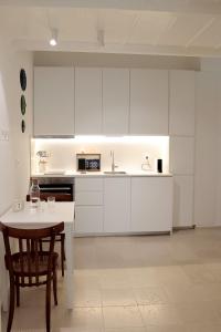 a kitchen with white cabinets and a table and a sink at Dimora Veneziani in Bisceglie