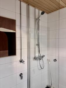 a shower in a bathroom with white tiles at Borg Areena - Stylish Studio Apt For 3 in Tampere
