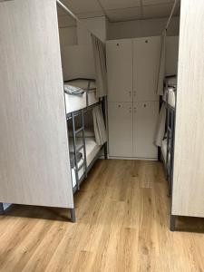 a room with three bunk beds and a wooden floor at Albergue Porta Real NO BIKE STORAGE in Santiago de Compostela