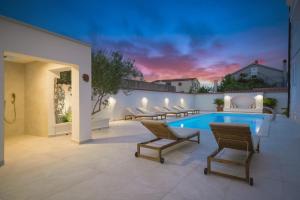a patio with a swimming pool and lounge chairs at Apartments Bianca Vodice in Vodice