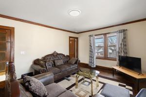 a living room with a leather couch and a television at College Area 3BR in Grand Rapids