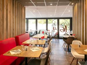 a restaurant with wooden tables and chairs and windows at ibis Montpellier Sud in Montpellier