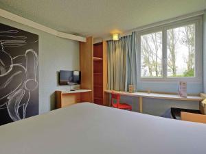 a room with a bed and a desk and a window at ibis Poitiers Beaulieu in Poitiers +29 photos
