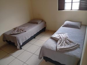 two beds in a room with a tiled floor at Restaurante e Hotel Campos in Nova Andradina