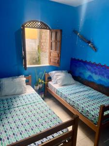 two beds in a room with blue walls at Casa caserinho in Lençóis