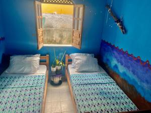 two beds in a blue room with a window at Casa caserinho in Lençóis