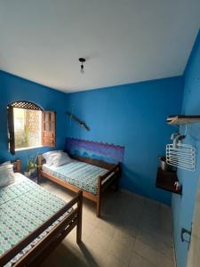 two beds in a room with a blue wall at Casa caserinho in Lençóis