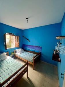 a room with two beds and a blue wall at Casa caserinho in Lençóis