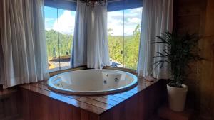 a large bath tub sitting in front of a window at Chalé Recanto do Pimenta 02 in Venda Nova do Imigrante +11 photos